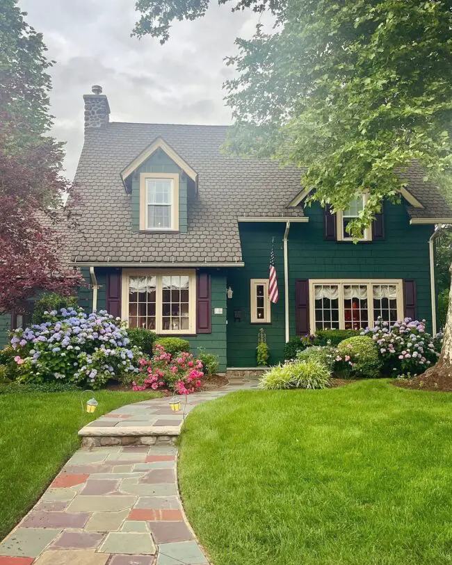 Green Cottage Surrounded by Vibrant Landscaping